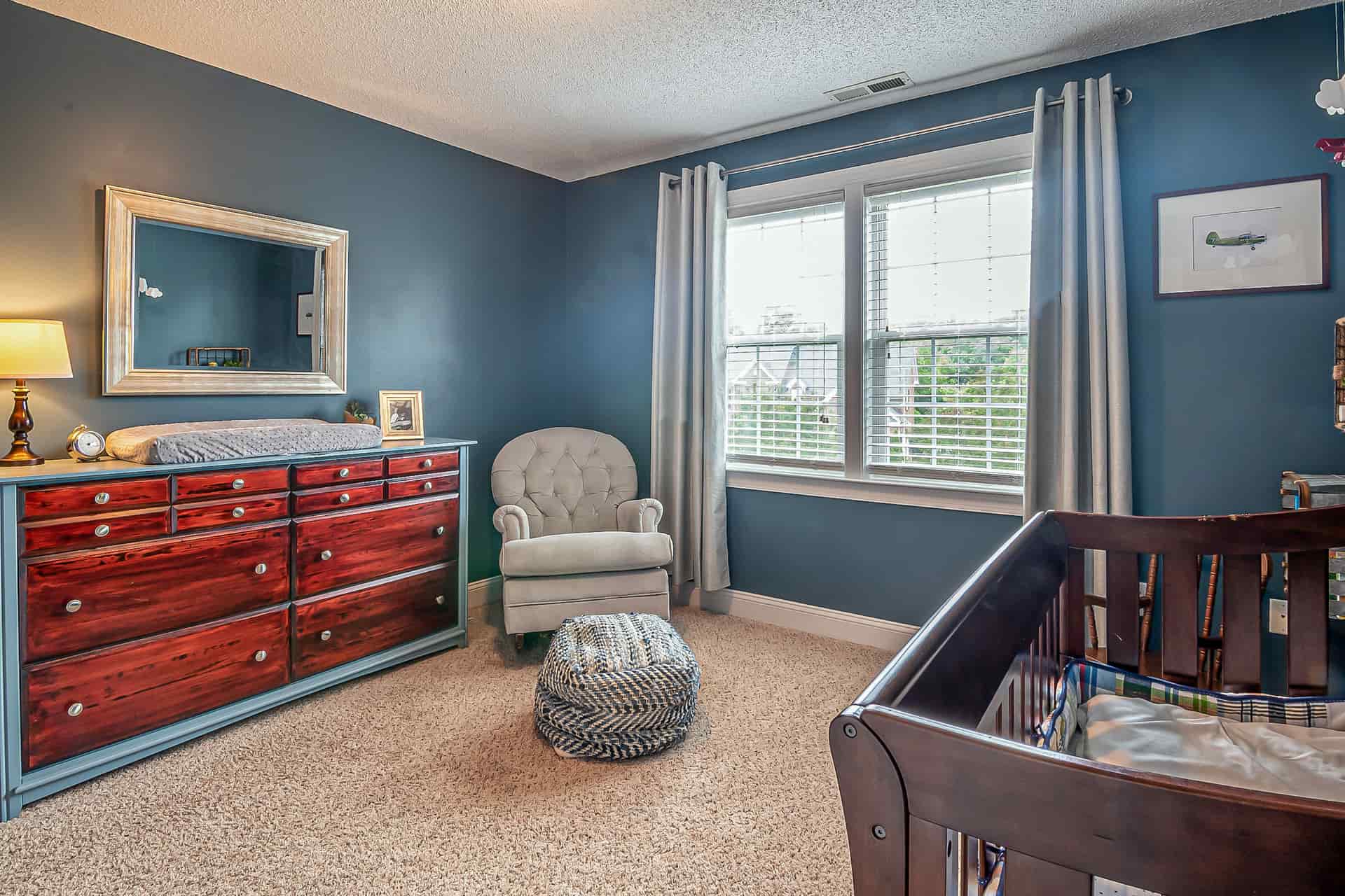 A tall dresser beside a crib in a nursery