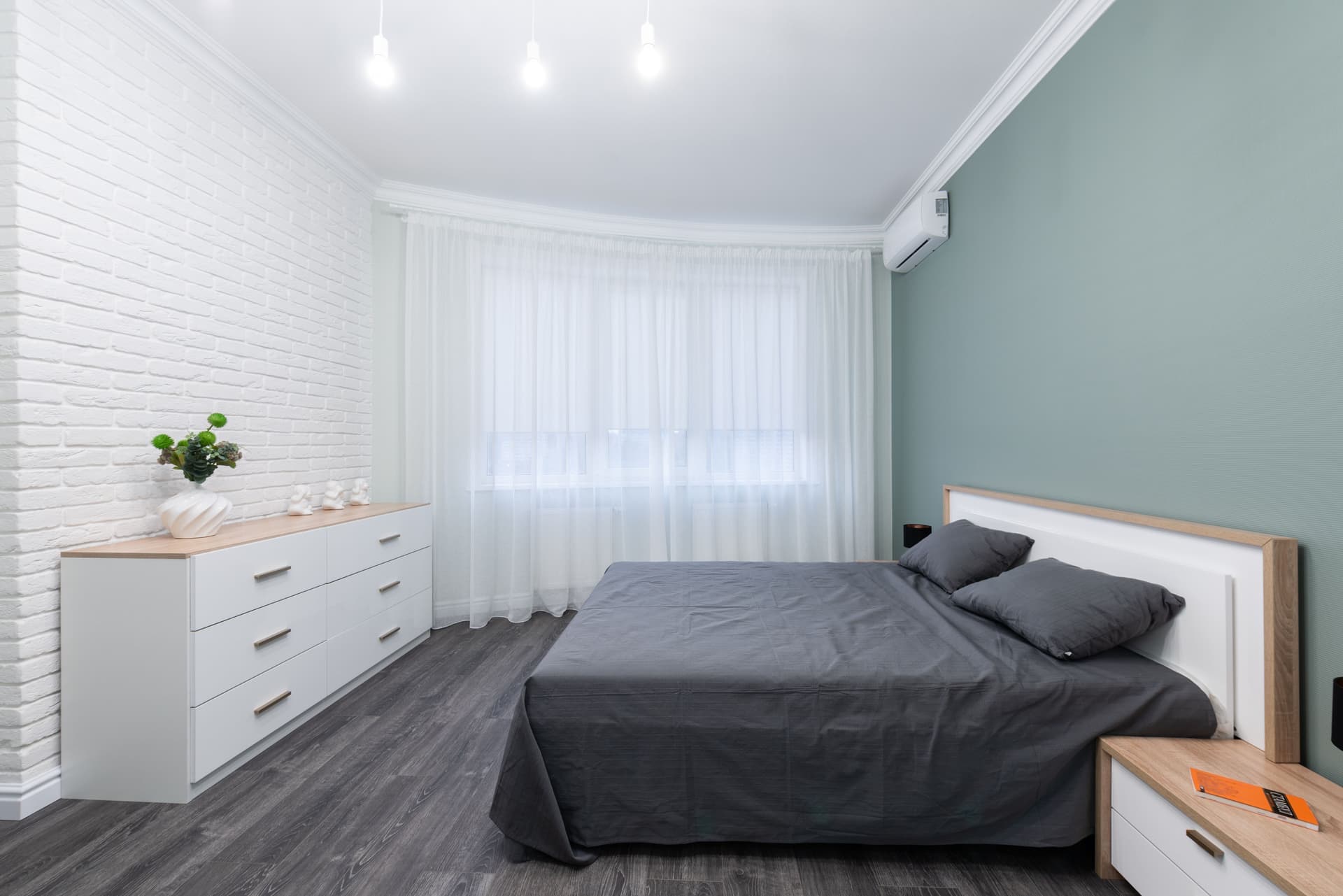 A wooden chest of drawers standing against a bedroom wall